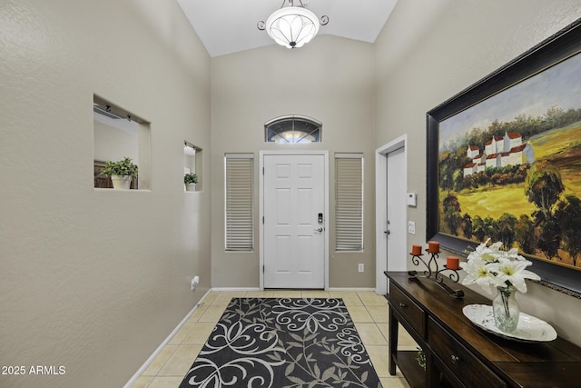 foyer featuring light tile patterned floors, high vaulted ceiling, and baseboards