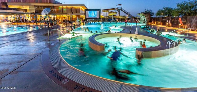 pool featuring a water slide, a community hot tub, and a patio