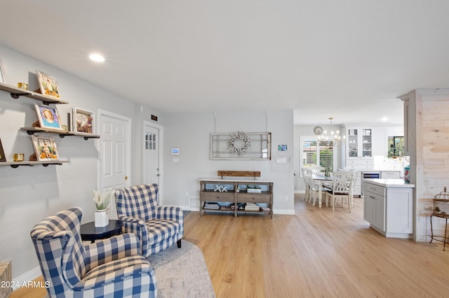 living room featuring wine cooler, an inviting chandelier, and light hardwood / wood-style flooring