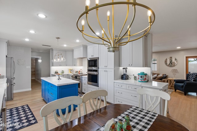 kitchen with a kitchen island, appliances with stainless steel finishes, white cabinetry, blue cabinetry, and an inviting chandelier