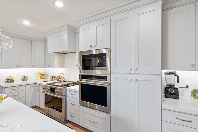 kitchen with premium range hood, appliances with stainless steel finishes, tasteful backsplash, white cabinetry, and hanging light fixtures