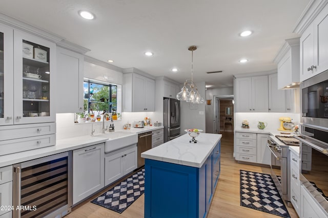 kitchen featuring appliances with stainless steel finishes, sink, wine cooler, hanging light fixtures, and a center island