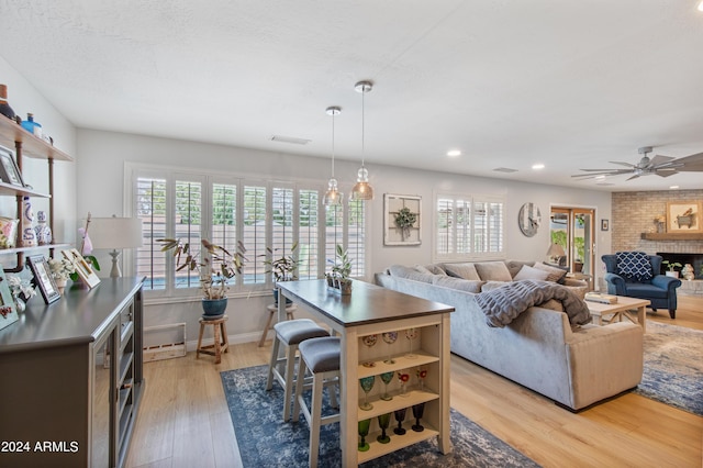 living room featuring ceiling fan, a fireplace, light hardwood / wood-style flooring, and a wealth of natural light