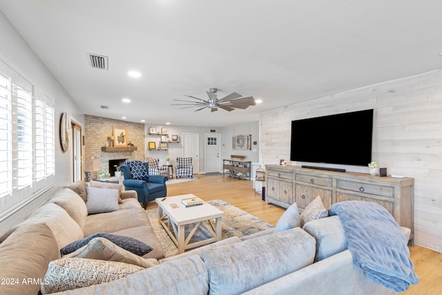 living room with ceiling fan, a fireplace, and light hardwood / wood-style flooring