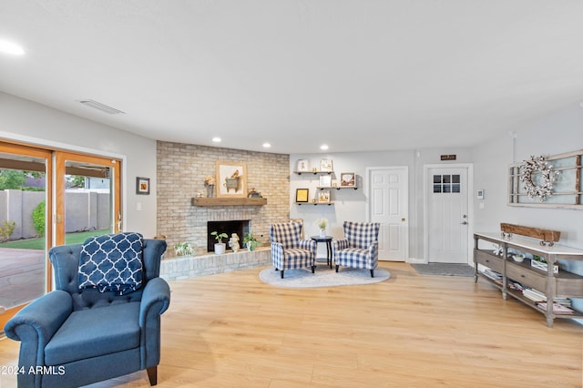 living room with a brick fireplace and light wood-type flooring