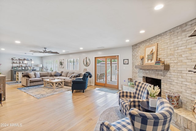 living room with ceiling fan, a fireplace, and light hardwood / wood-style floors