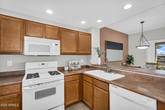 kitchen with recessed lighting, white appliances, brown cabinets, and a sink