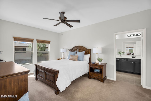 bedroom featuring baseboards, light colored carpet, a sink, and ensuite bath