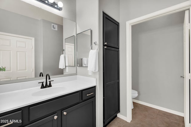 bathroom featuring visible vents, baseboards, toilet, tile patterned floors, and vanity