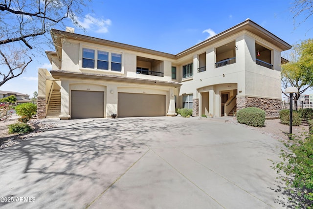 view of front facade featuring a garage, concrete driveway, stone siding, stairs, and stucco siding