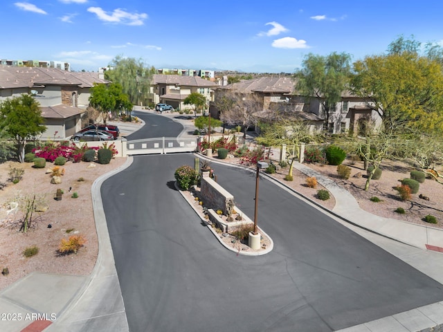 view of road featuring curbs, a gated entry, sidewalks, and a residential view