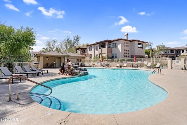 community pool featuring a residential view, a patio area, and fence