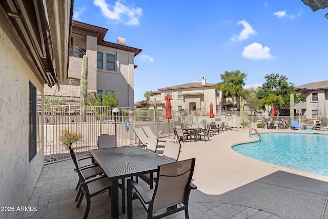 community pool with a patio area, fence, and a residential view