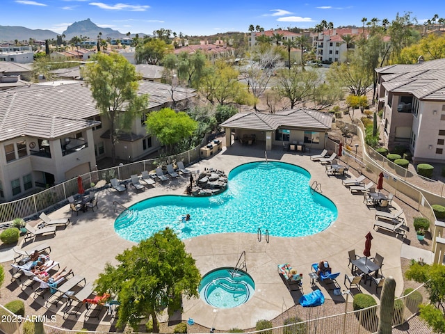 community pool featuring a patio, a residential view, fence, and a mountain view