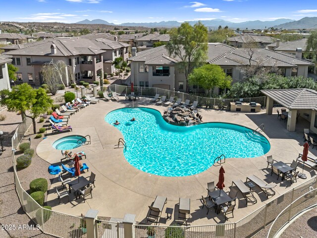 community pool with a residential view, a mountain view, a patio, and fence