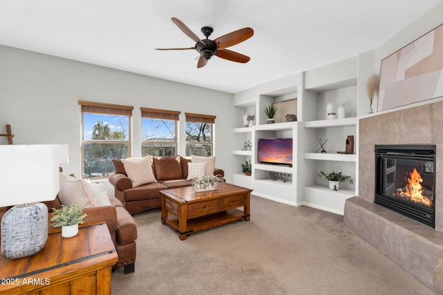 carpeted living room with built in shelves, ceiling fan, and a fireplace