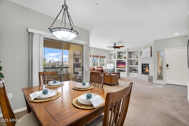 dining space with carpet floors, baseboards, a ceiling fan, and a tile fireplace