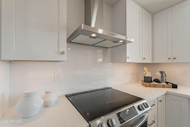 kitchen with electric stove, backsplash, white cabinetry, light stone countertops, and wall chimney exhaust hood