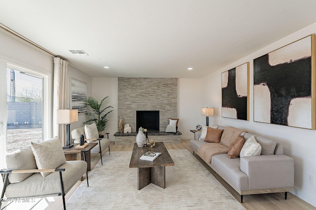 living room with light wood finished floors, baseboards, a fireplace, and visible vents