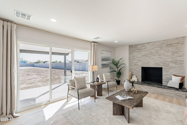 living room featuring a fireplace, visible vents, and wood finished floors