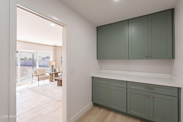 interior space featuring green cabinets, light countertops, light wood-type flooring, and baseboards