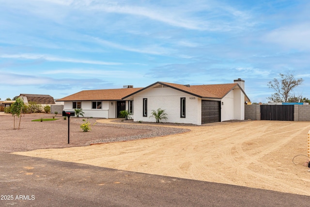 ranch-style home featuring driveway, an attached garage, a gate, fence, and brick siding