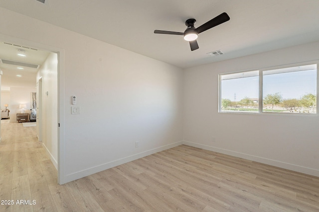 spare room with light wood-style floors, baseboards, visible vents, and a ceiling fan