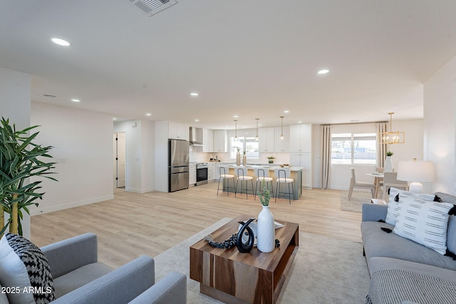 living area with light wood finished floors, baseboards, visible vents, an inviting chandelier, and recessed lighting