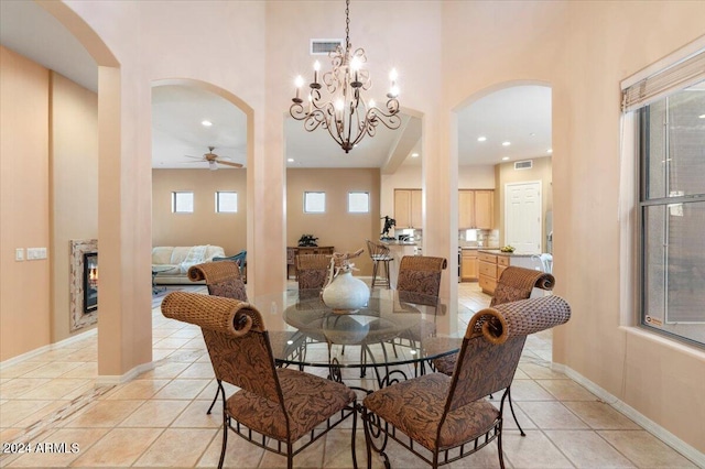 dining area featuring light tile patterned flooring and ceiling fan with notable chandelier