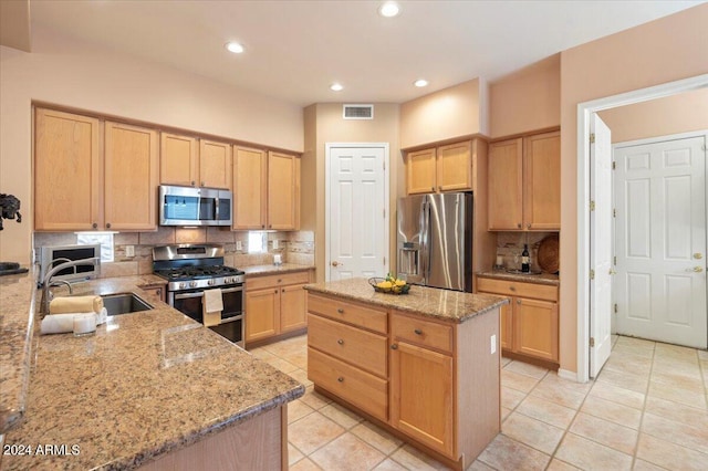 kitchen with light stone counters, backsplash, light brown cabinets, stainless steel appliances, and sink