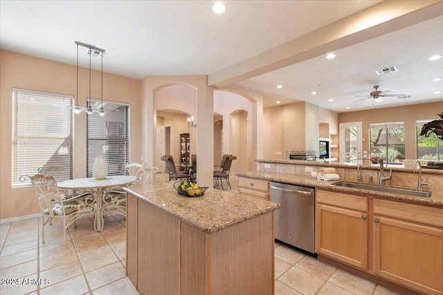 kitchen with sink, stainless steel dishwasher, decorative light fixtures, a center island, and light stone countertops