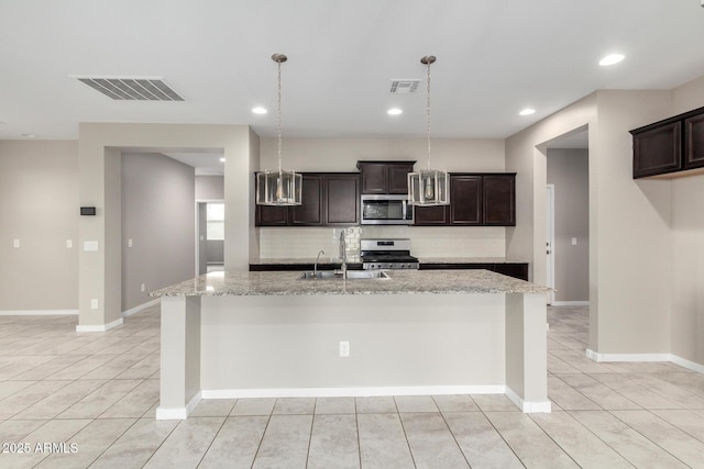 kitchen featuring pendant lighting, sink, appliances with stainless steel finishes, a kitchen island with sink, and dark brown cabinets