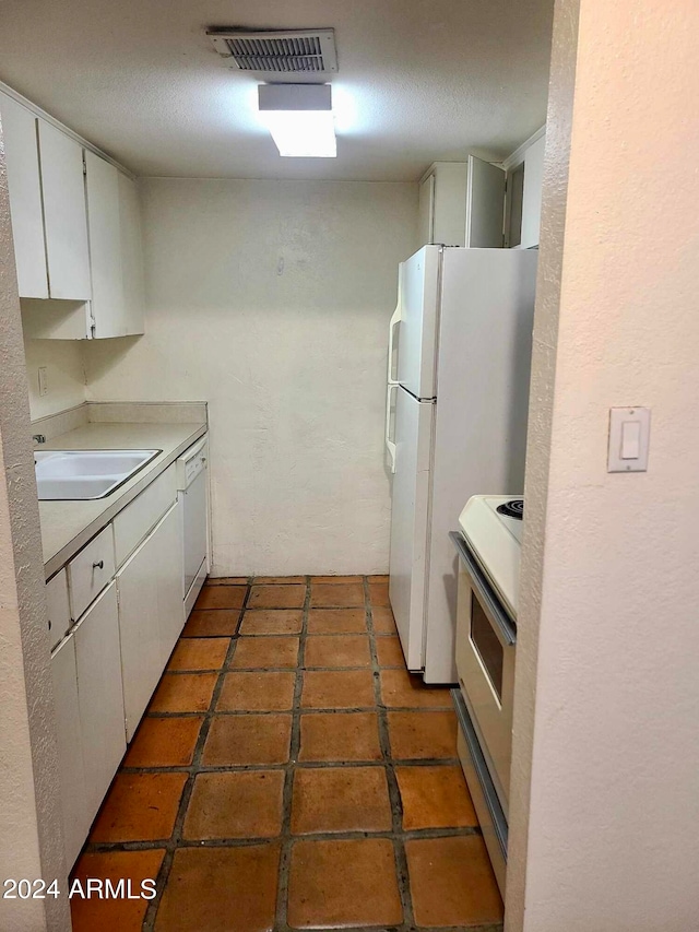 kitchen with white appliances, white cabinetry, and sink