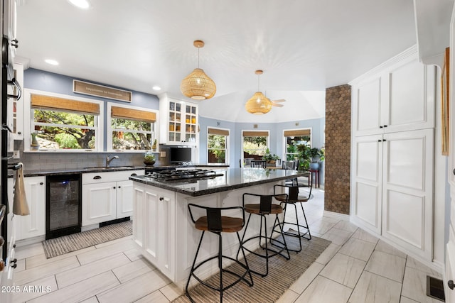 543 S Hassayampa Dr, Prescott, AZ 86303 - kitchen featuring beverage cooler, a kitchen island, white cabinets, stainless steel gas cooktop, and a kitchen bar