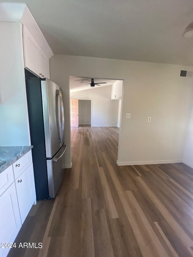 kitchen with light stone countertops, ceiling fan, dark wood-type flooring, white cabinetry, and stainless steel refrigerator