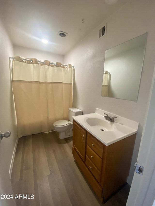 bathroom with toilet, vanity, wood-type flooring, and walk in shower