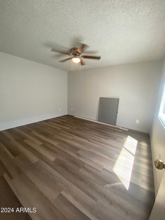 spare room with a textured ceiling, ceiling fan, and dark wood-type flooring