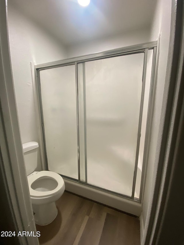 bathroom with a shower with door, wood-type flooring, and toilet