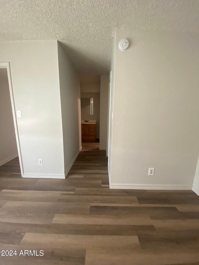 corridor featuring dark hardwood / wood-style flooring and a textured ceiling