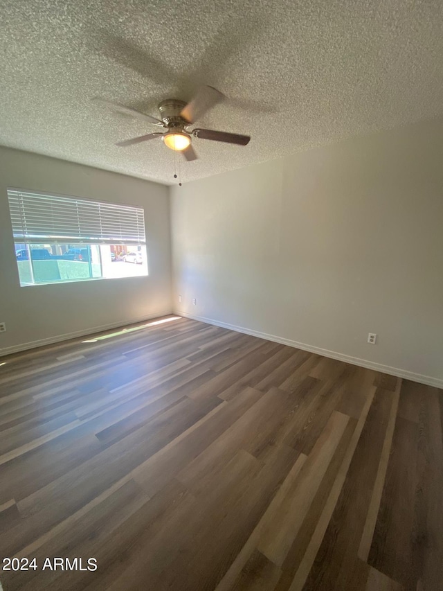 empty room featuring a textured ceiling, dark hardwood / wood-style floors, and ceiling fan