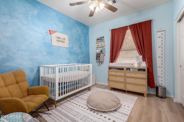 5401 S Dove Holw, Buckeye, AZ 85326 - bedroom featuring wood finished floors, a crib, baseboards, and a ceiling fan