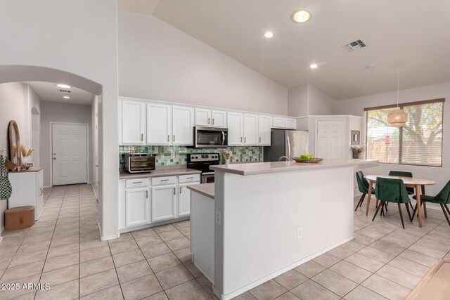 5401 S Dove Holw, Buckeye, AZ 85326 - kitchen featuring stainless steel appliances, light tile patterned flooring, tasteful backsplash, high vaulted ceiling, and arched walkways