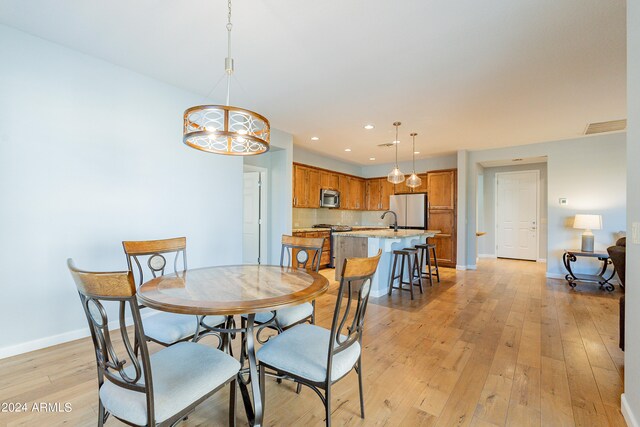 dining room featuring a notable chandelier, light wood-type flooring, and sink