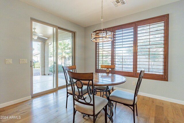 dining area with light hardwood / wood-style flooring, ceiling fan with notable chandelier, and a healthy amount of sunlight