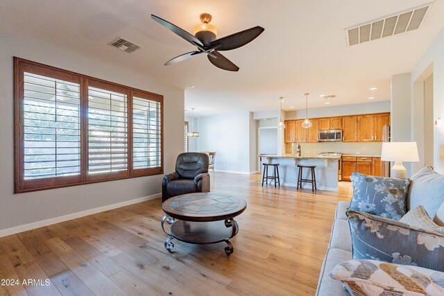 living room featuring ceiling fan, sink, and light hardwood / wood-style floors