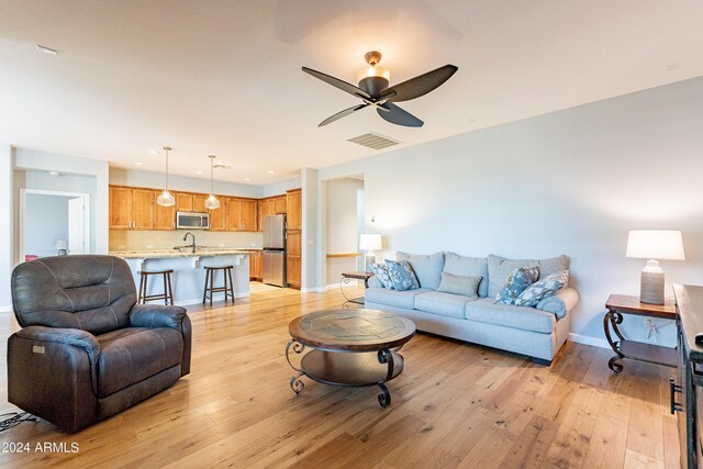 living room with ceiling fan, sink, and light hardwood / wood-style floors