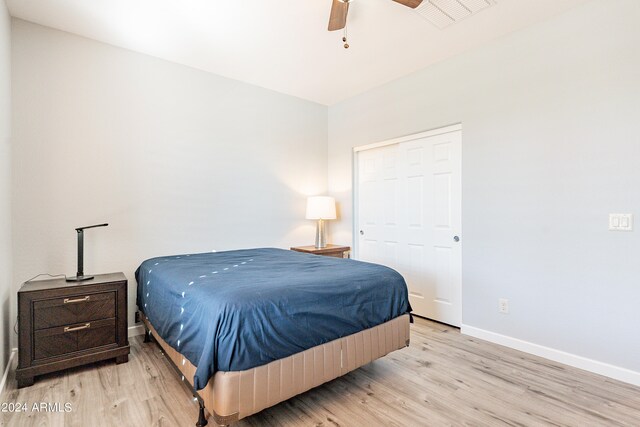 bedroom with light hardwood / wood-style floors, ceiling fan, and a closet