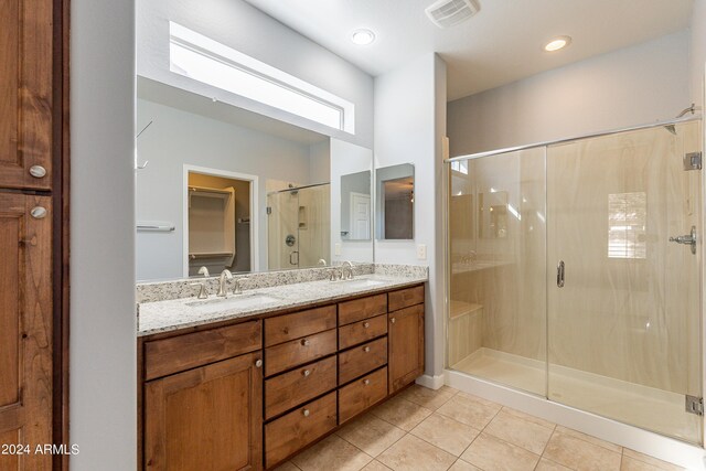 bathroom with walk in shower, vanity, and tile patterned floors