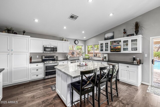 15027 N 61st Pl, Scottsdale, AZ 85254 - kitchen featuring visible vents, lofted ceiling, stainless steel appliances, dark wood-type flooring, and backsplash