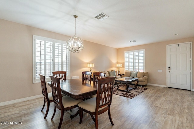 dining room with light wood-type flooring, visible vents, baseboards, and an inviting chandelier